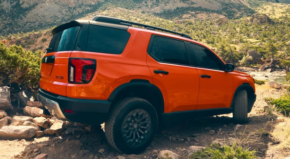 An orange 2026 Honda Passport Trailsport is shown from the rear at an angle.