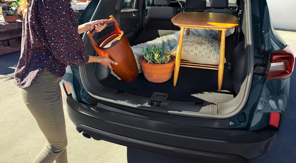 A woman loading home decor into the cargo area of a 2025 Ford Escape.