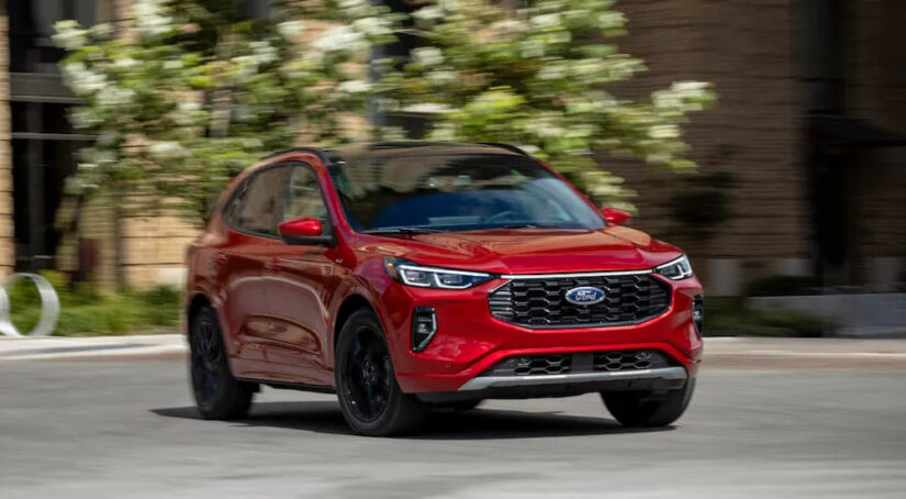 A red 2025 Ford Escape ST-Line Elite driving to a Ford dealer.