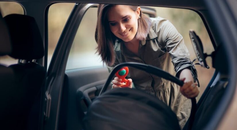 A mother is shown installing a car seat in a vehicle.