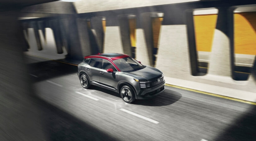 A grey and red 2025 Nissan Kicks SR is shown driving to a Nissan dealer.