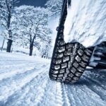 A close-up of a tire is shown on a snowy road.