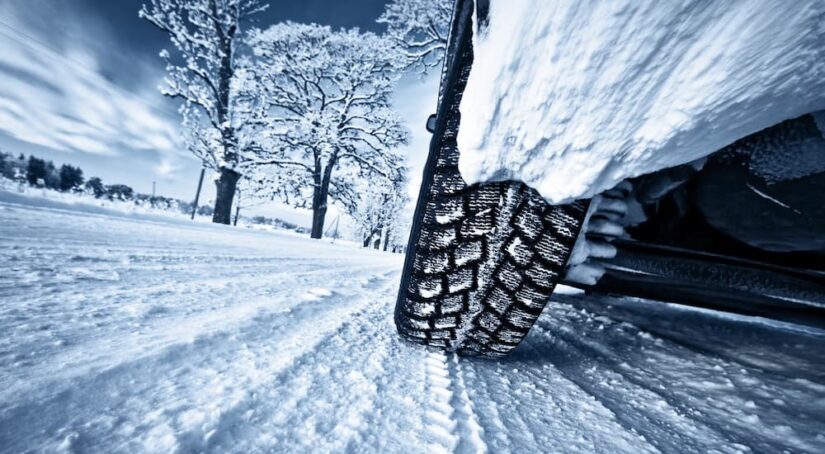 A close-up of a tire is shown on a snowy road.