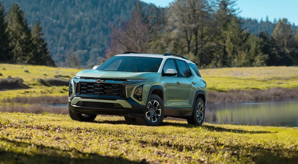 A green 2025 Chevy Equinox ACTIV is shown parked near a pond.