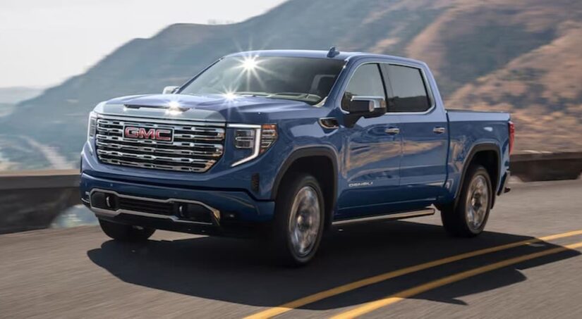 A blue 2025 GMC Sierra 1500 is shown driving to visit a GMC dealer.