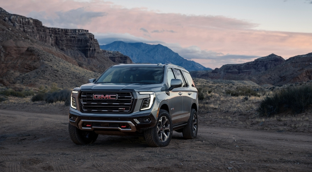 A grey 2025 GMC Yukon AT4 is shown from the front at an angle.