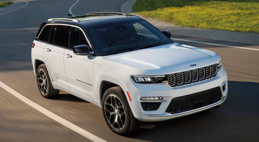 A white 2025 Jeep Grand Cherokee is shown driving to a Jeep dealer.