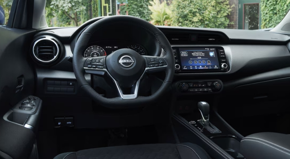 The black interior of a 2025 Nissan Kicks Play is shown from the driver's seat.