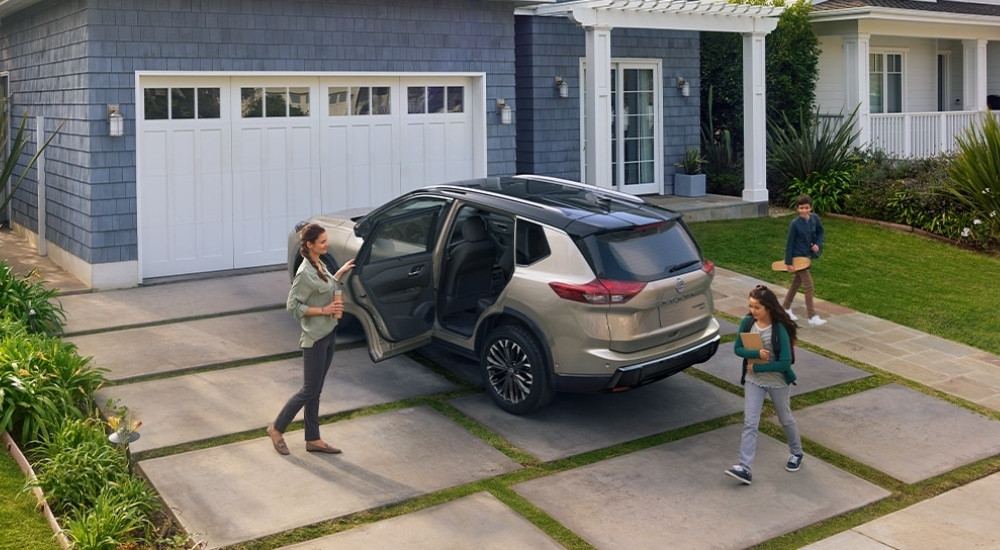 A tan 2025 Nissan Rogue is shown from the rear at an angle.