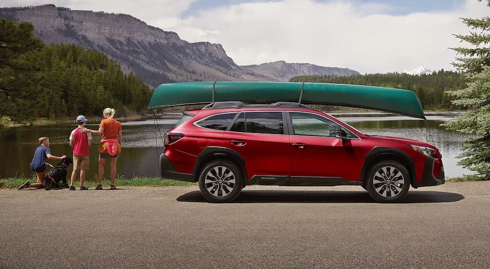 A red 2025 Subaru Outback Limited is shown parked near a lake.