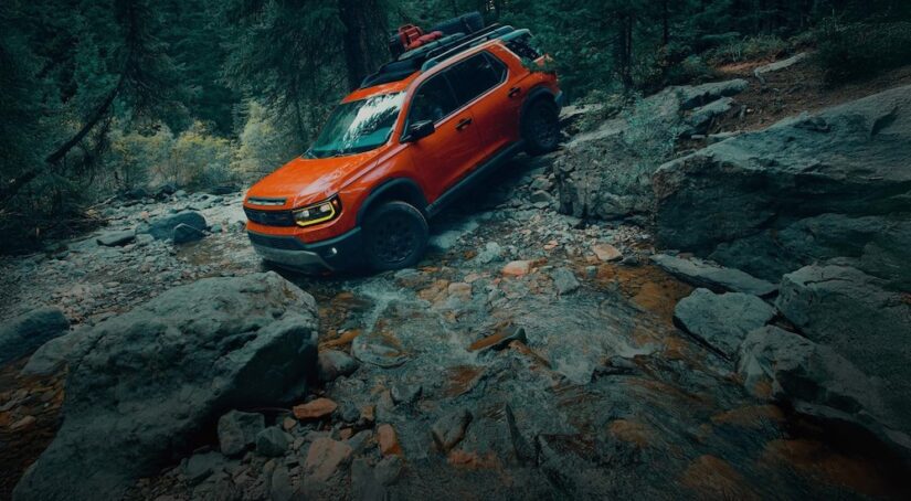 An orange 2026 Honda Passport TrailSport is shown off-roading.