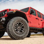 Low angle view of a red 2025 Jeep Wrangler for sale parked off-road.