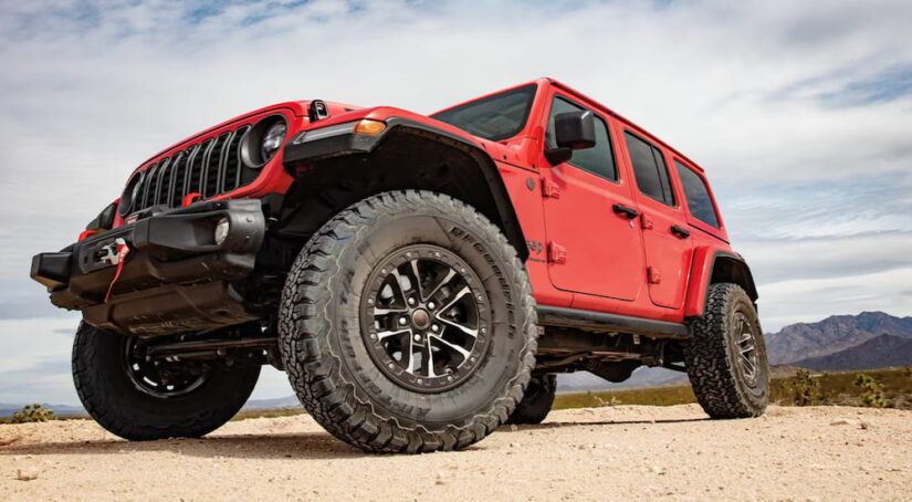 Low angle view of a red 2025 Jeep Wrangler for sale parked off-road.