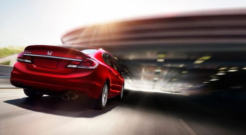 A red 2014 Honda Civic SI is shown driving under a bridge.