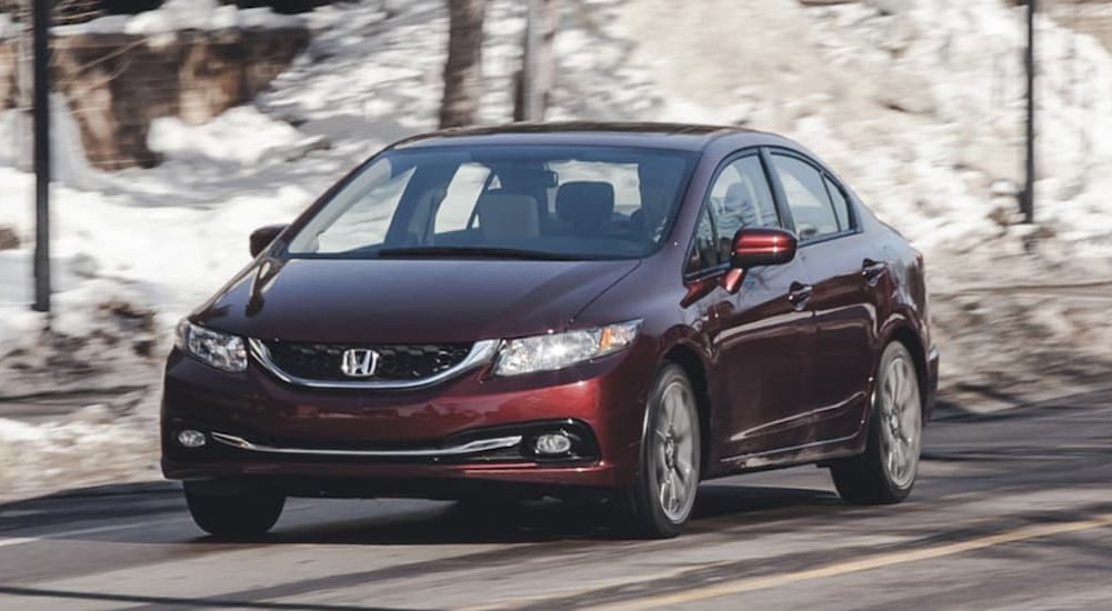 A burgundy 2014 Honda Civic is shown driving on a snowy day.