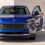 Front angle view of a woman entering a blue 2025 Buick Envision.