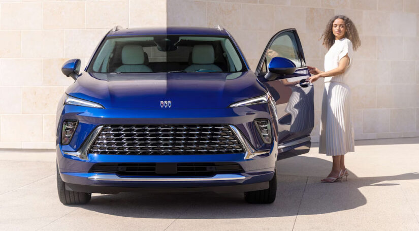 Front angle view of a woman entering a blue 2025 Buick Envision.