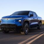 A blue 2025 Chevy Silverado EV RST driving from a dealer with electric vehicles for sale.