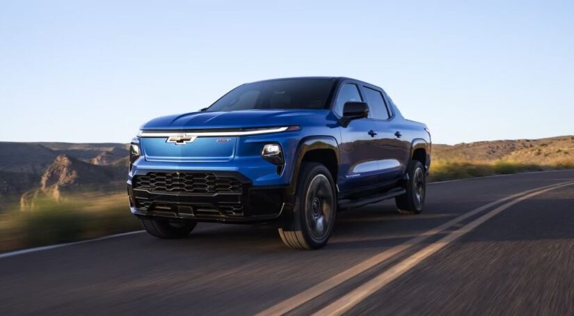 A blue 2025 Chevy Silverado EV RST driving from a dealer with electric vehicles for sale.