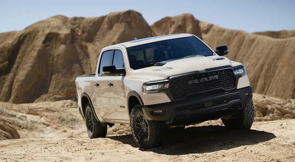 A white 2025 Ram 1500 Rebel parked off-road in a desert.