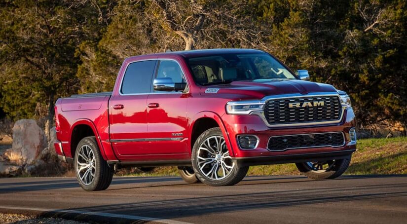 A red 2025 Ram 1500 Tradesman driving from a dealer with a Ram 1500 for sale.