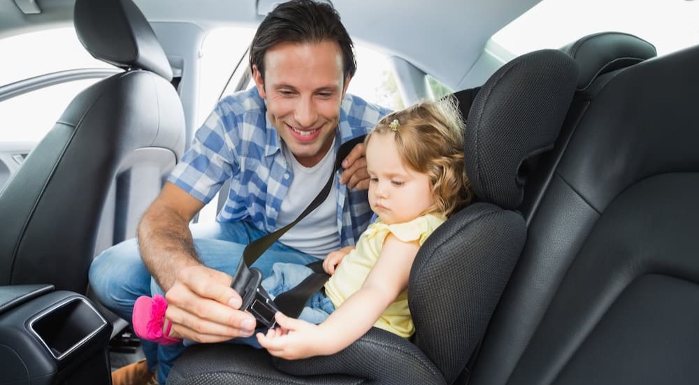 A person is shown unbuckling a child from a car seat.