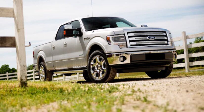 A white 2014 Ford F-150 Lariat is shown parked near a wooden fence.