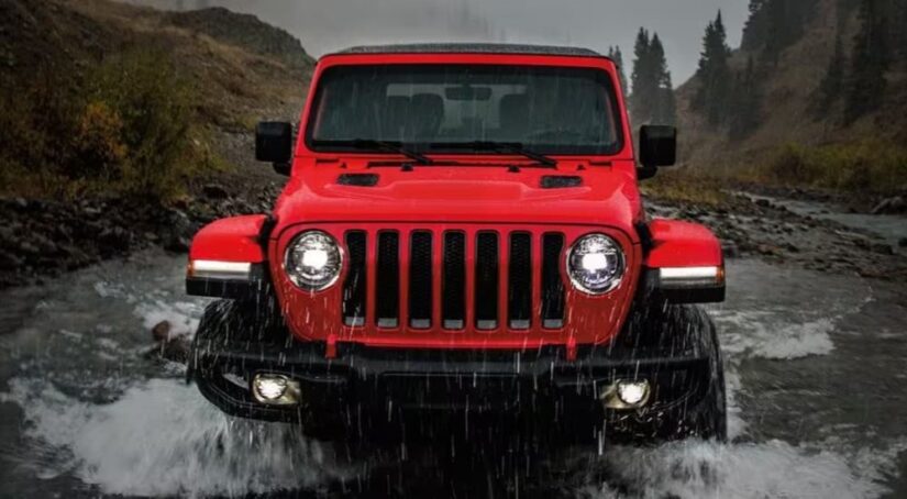 Front angle view of a red 2022 Jeep Wrangler fording a shallow creek.