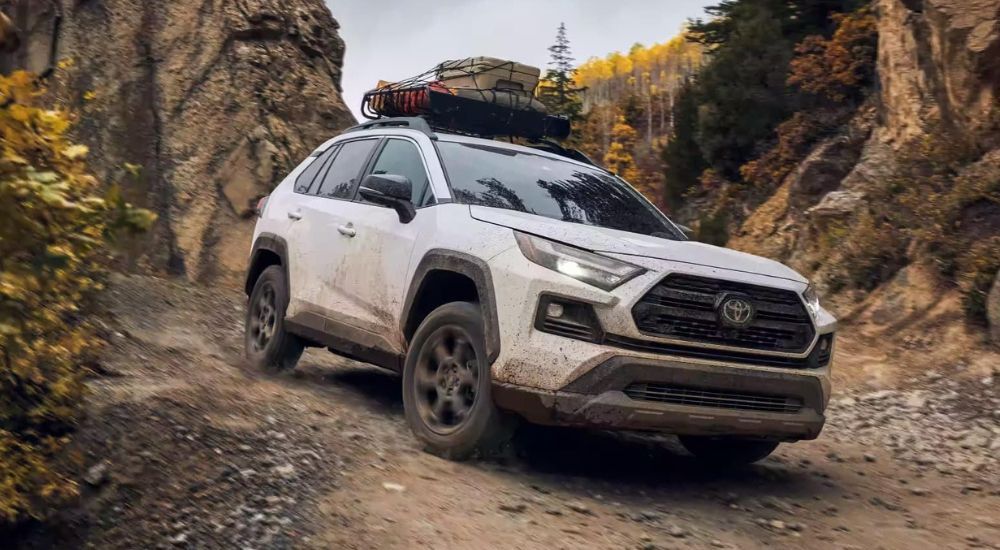 A white 2023 Toyota RAV4 TRD Off-Road driving off-road down a rocky hill.