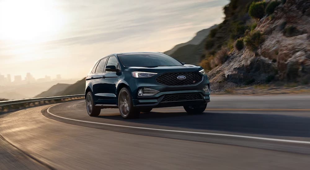 A blue 2024 Ford Edge driving down a winding road.