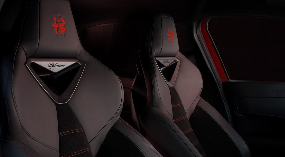 A close-up of the black and red seats in a 2025 Alfa Romeo Junior Elettrica are shown.