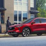 A red 2025 Ford Escape Platinum is shown parked on a city street.