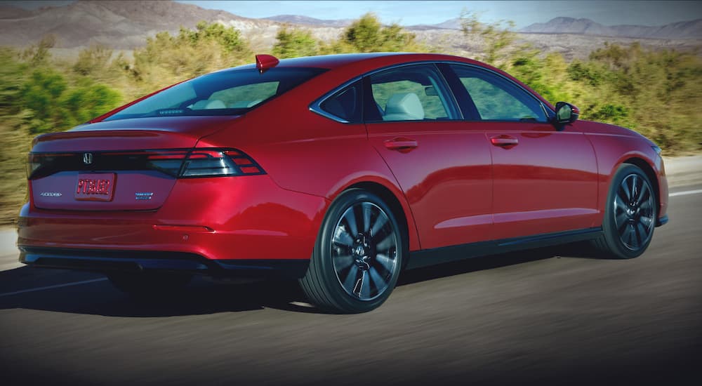 A red 2025 Honda Accord Hybrid is shown from the rear at an angle.