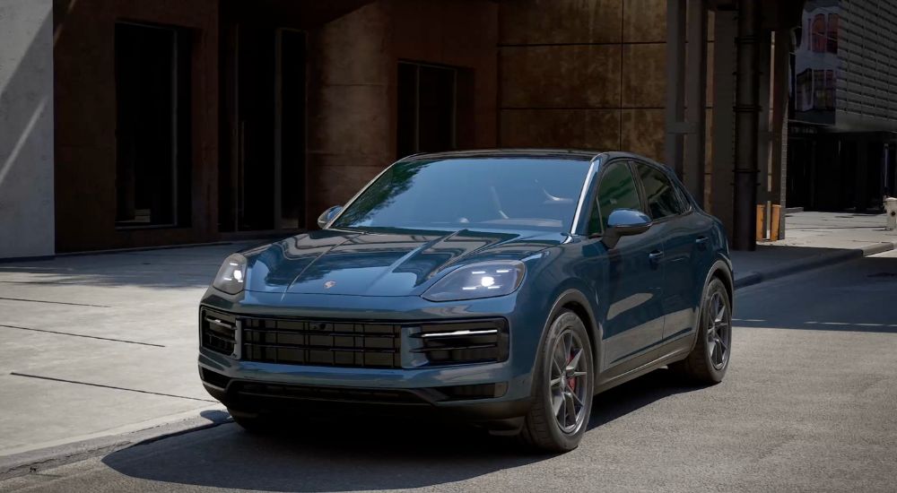 A blue 2025 Porsche Cayenne S Coupe parked on the side of a street.