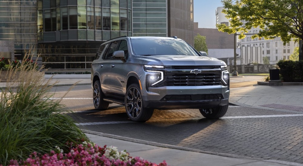 A silver 2025 Chevy Tahoe for sale driving through a city.