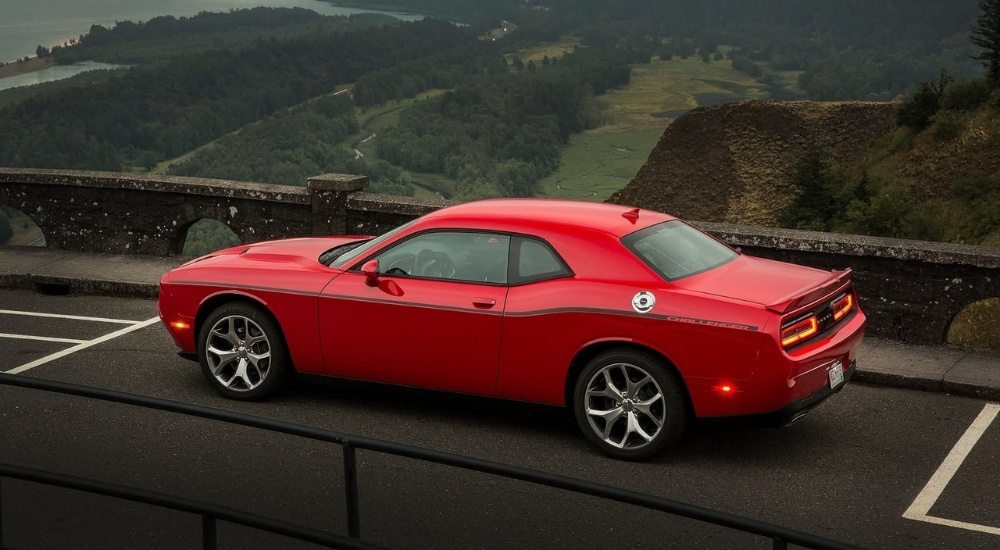 A red 2015 Dodge Challenger for sale is shown parked at an overlook.