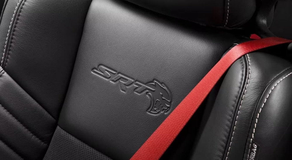 A close up shows the red seatbelt against a black leather seat in a 2023 Dodge Challenger SRT Hellcat.