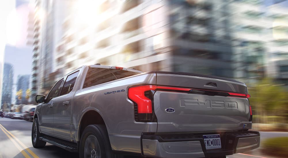 A silver 2022 Ford F-150 Lightning is shown from the rear at an angle.