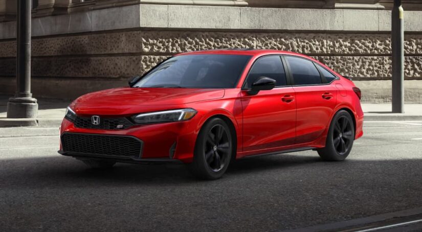 A red 2025 Honda Civic Si parked by a curb.