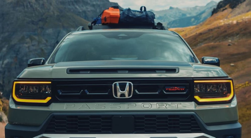 A green 2026 Honda Passport TrailSport Elite is shown parked near mountains.