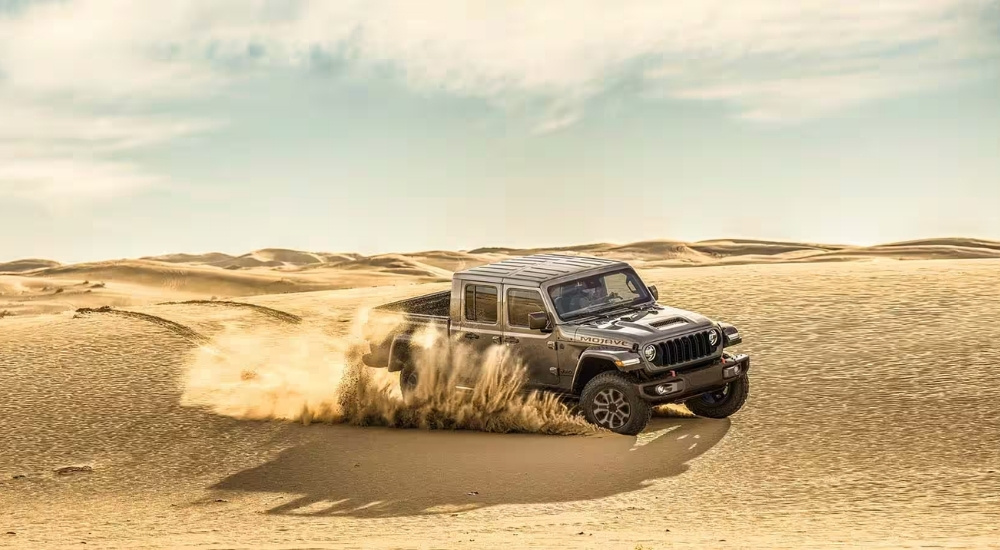 A grey 2025 Jeep Gladiator Mojave X is shown kicking up dust.