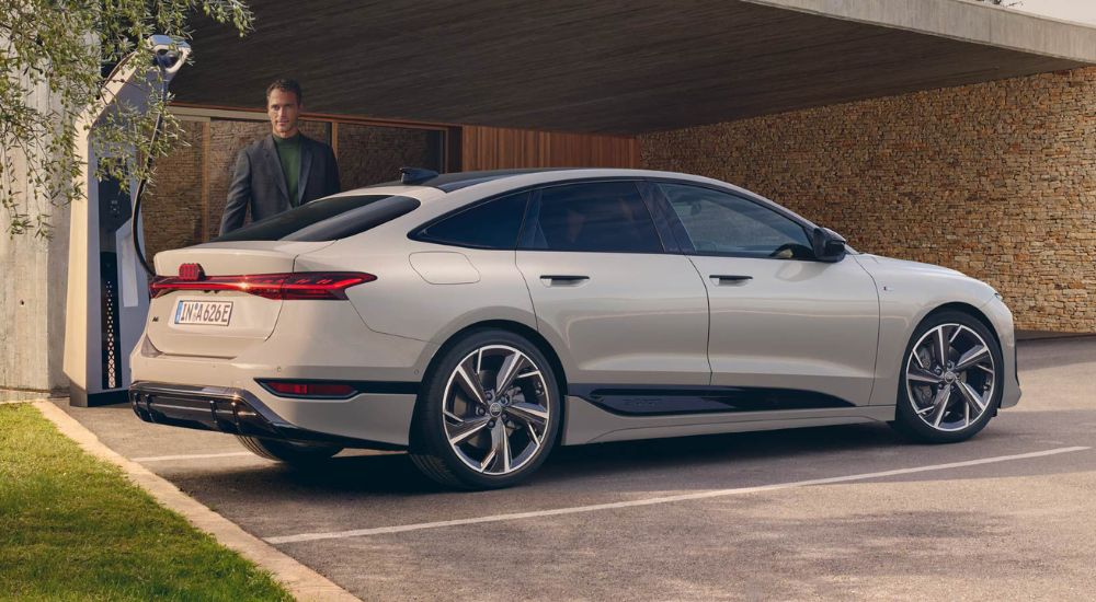 A person is shown charging a 2026 Audi A6 Sportback e-tron.