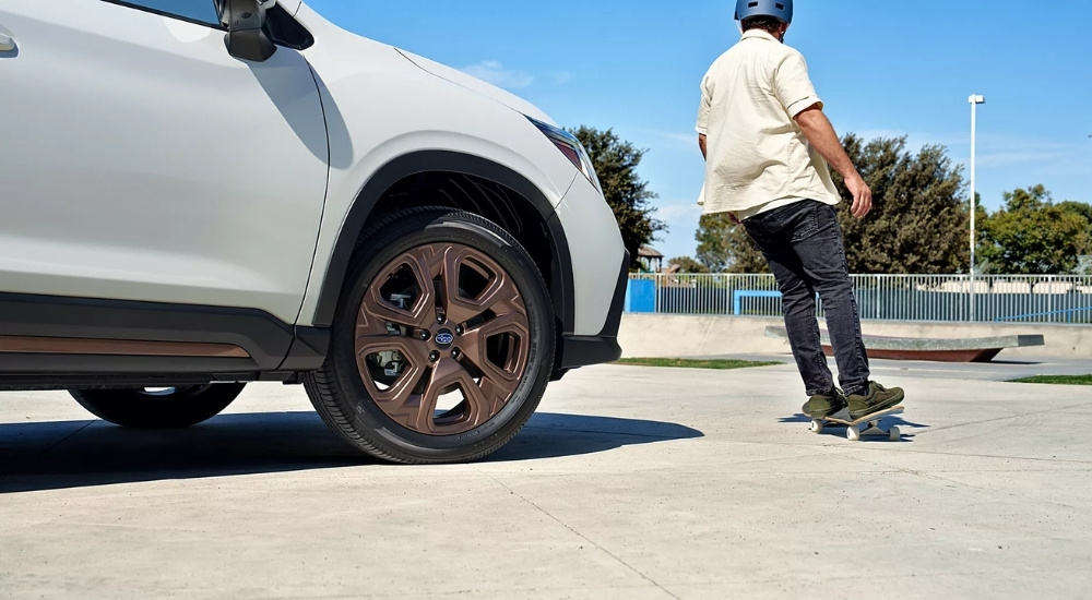 A white 2025 Subaru Ascent Bronze Edition is shown near a skateboarder.