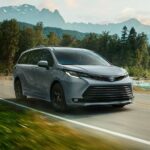 A grey 2025 Toyota Sienna Woodland Edition driving past a body of water.