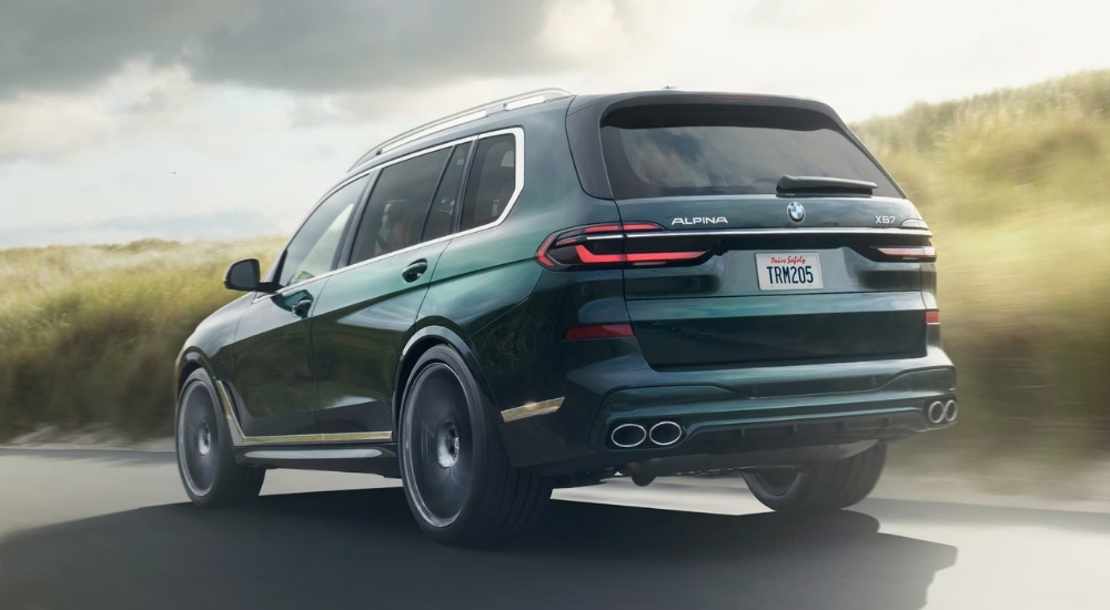 A green 2026 BMW ALPINA XB7 is driving on a highway.