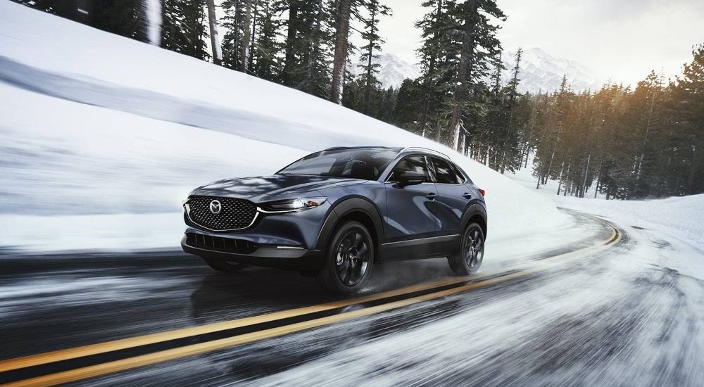 A black 2025 Mazda CX-30 driving down a snowy road.
