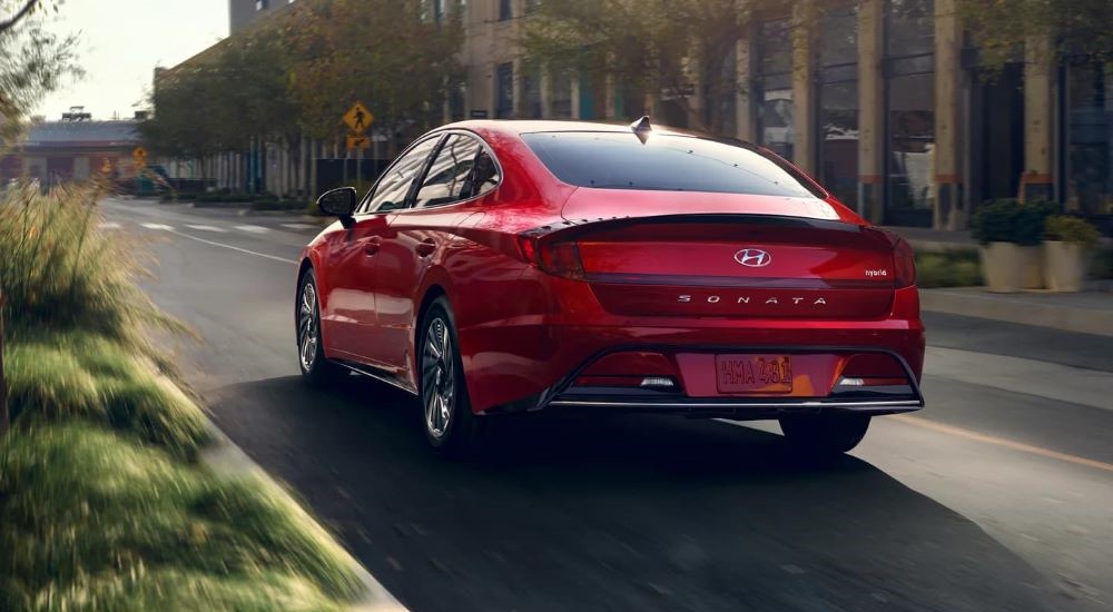 Back of a red 2022 Hyundai Sonata Hybrid driving down the road