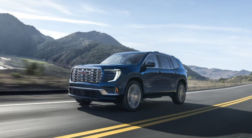 Blue 2025 GMC Acadia Denali driving on highway