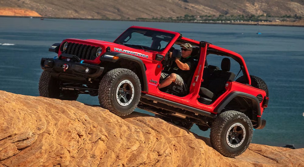A red 2025 Jeep Wrangler Rubicon is shown driving off-road.