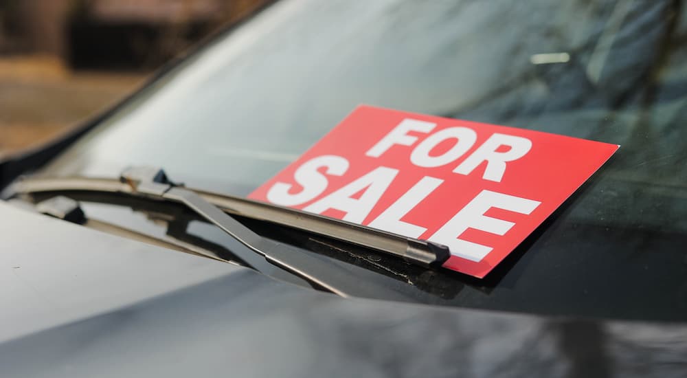 A red and white for sale sign on a car windshield
